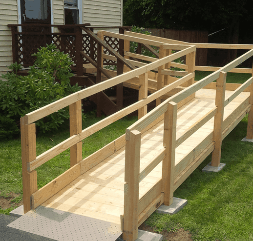 A custom-built timber ramp with picket handrails on both sides and a tactile paving pad at its foot