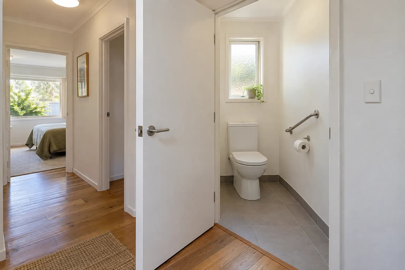 A separate toilet with its door opened outwards into the hallway, leaving the floor inside clear
