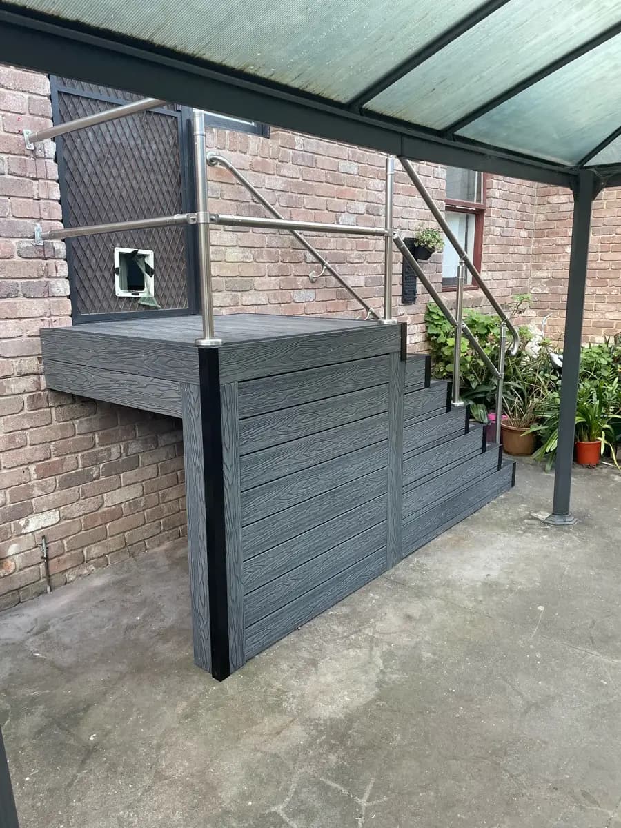 Grey composite steps and a landing built under a carport roof, with a stainless handrail and a balustrade
