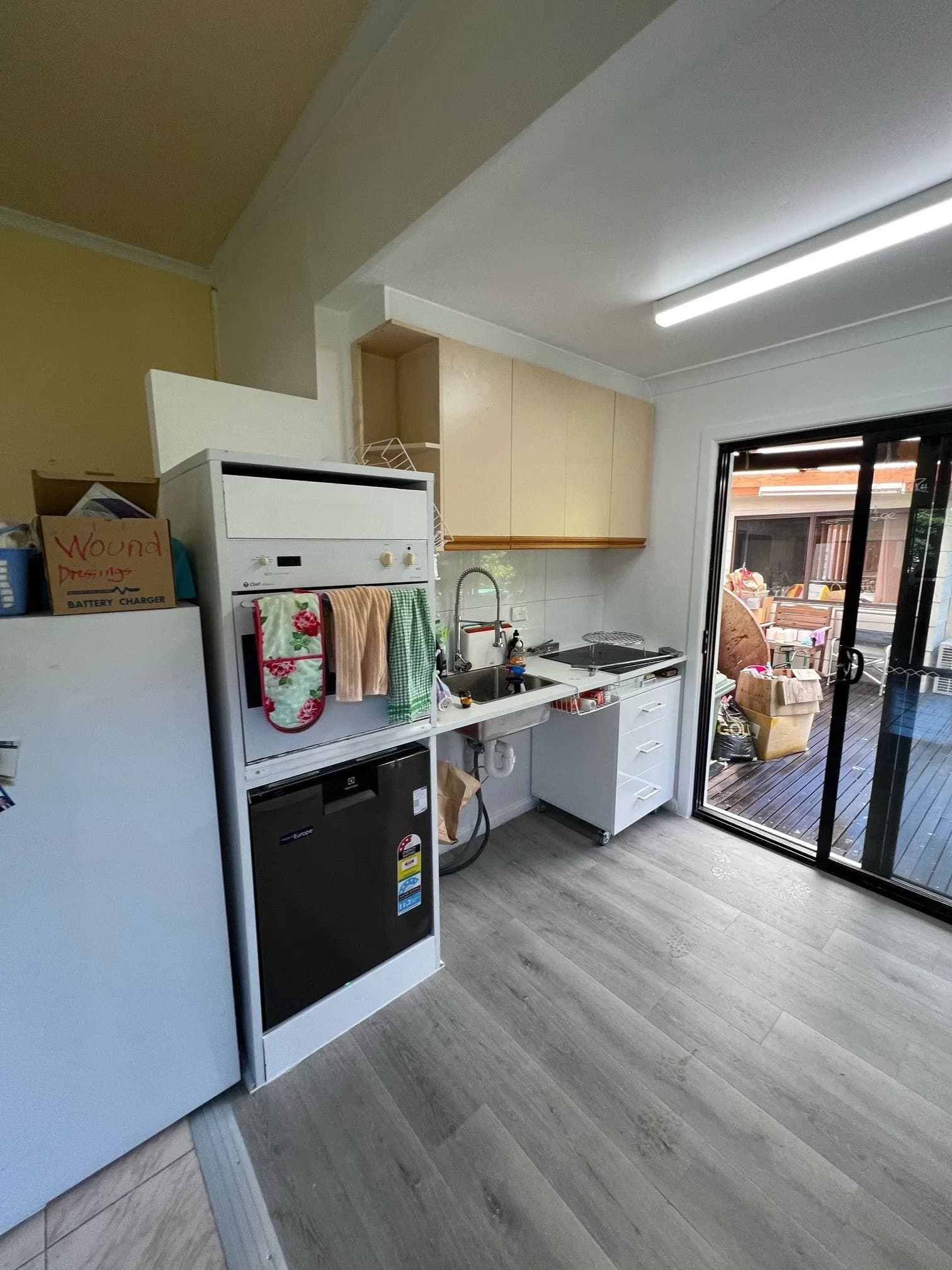 A kitchen with a lowered bench run, a wall oven at reachable height, and a clear path through to the back door