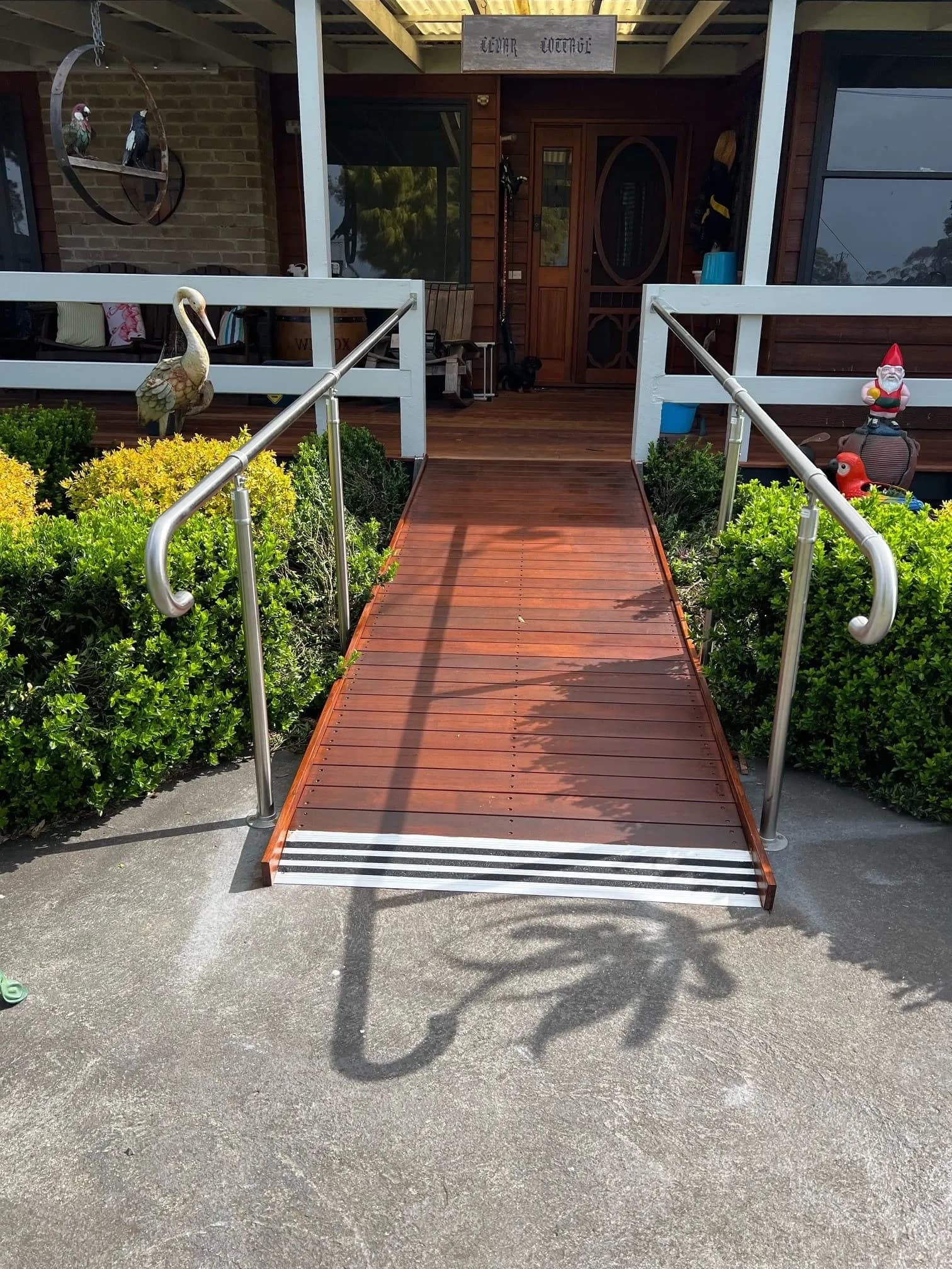 A timber ramp with stainless steel handrails on both sides leading up to a front entrance