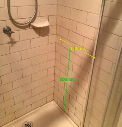A bathroom wall marked with measurements showing where a grab rail will be fixed