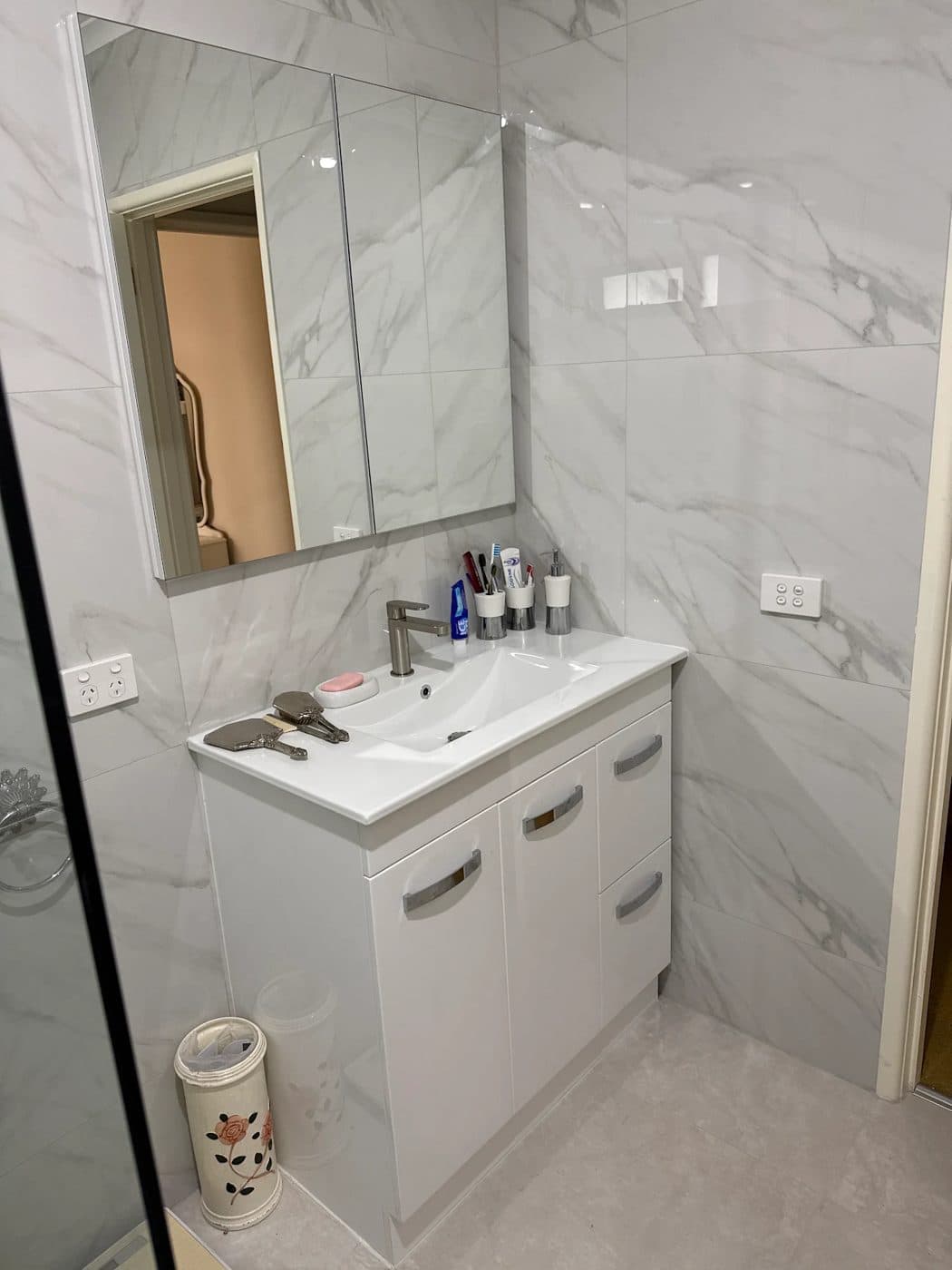 A new wide basin and vanity beneath a mirrored cabinet in the renovated bathroom