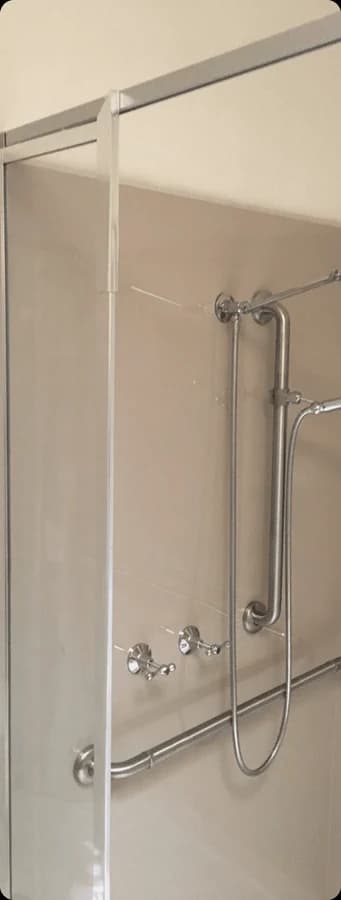 A fixed glass shower panel with a silver trim