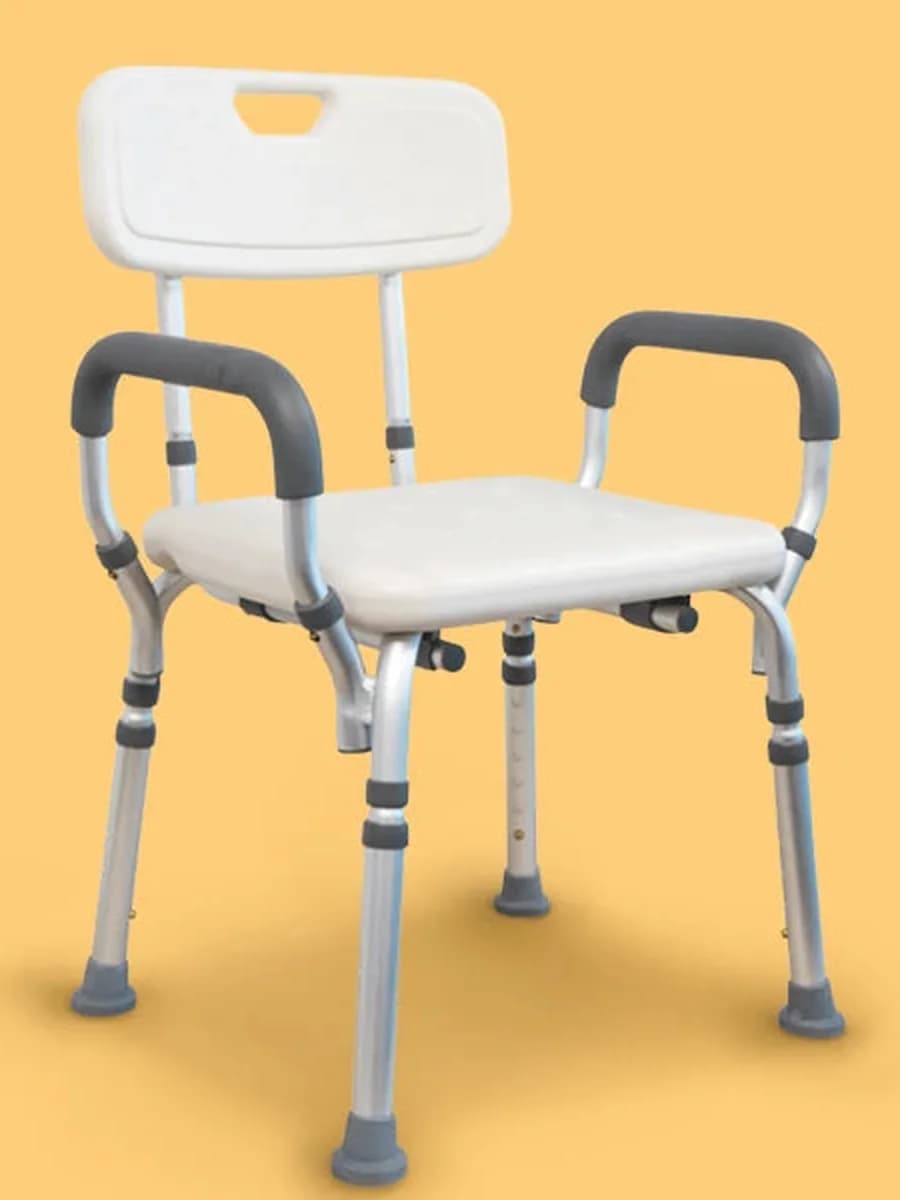 A white shower chair with padded armrests, a backrest, and height-adjustable legs