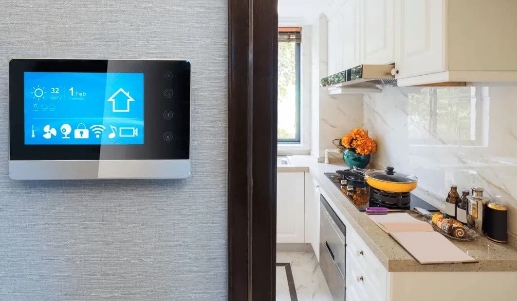 A wall-mounted smart home control panel showing lighting and climate controls, beside a kitchen doorway