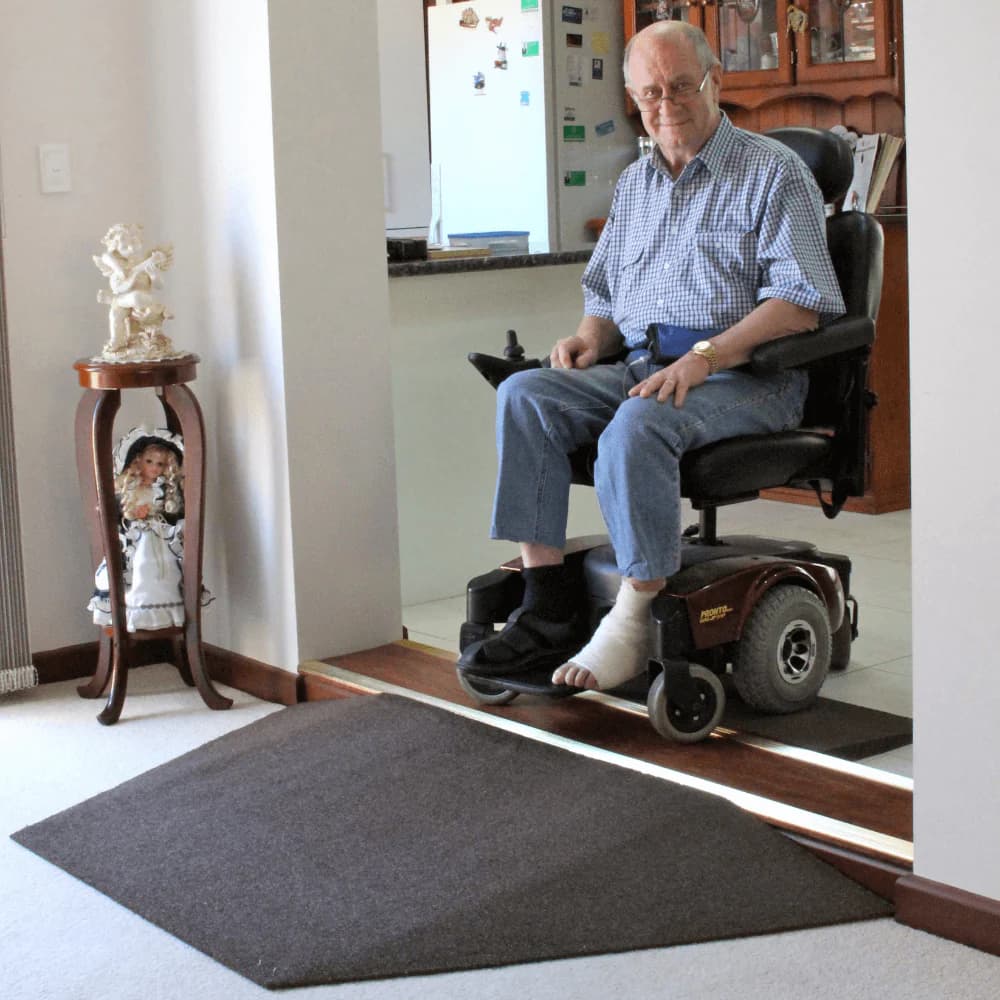 A black rubber threshold ramp with tapered winged edges laid at a sliding glass door onto a timber floor