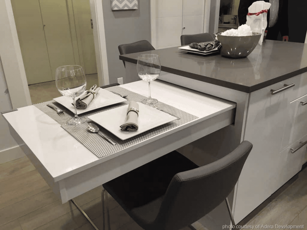 A kitchen with a lowered white table pulled out from under the benchtop, set at seated height with a chair tucked beneath