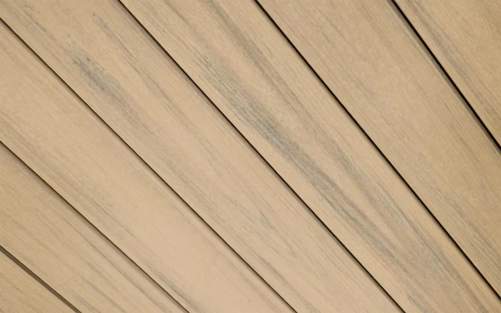 Composite decking boards in a pale grey-brown tone, photographed close up to show the woodgrain texture