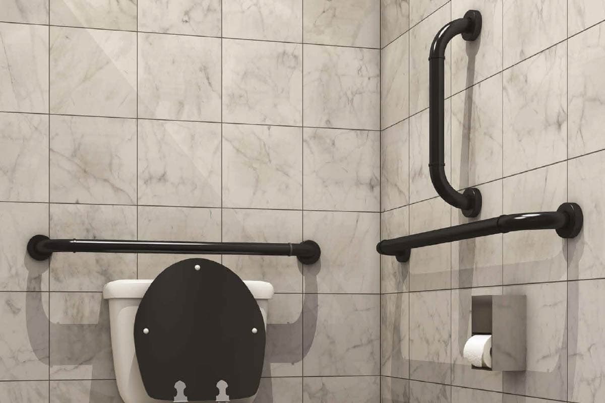 A marble-tiled bathroom with black horizontal and vertical grab rails fitted beside the toilet and along the shower wall