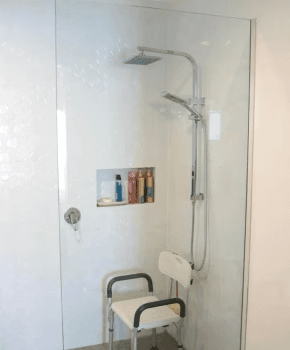A level-access shower with a fold-down seat and a handheld shower on a vertical rail