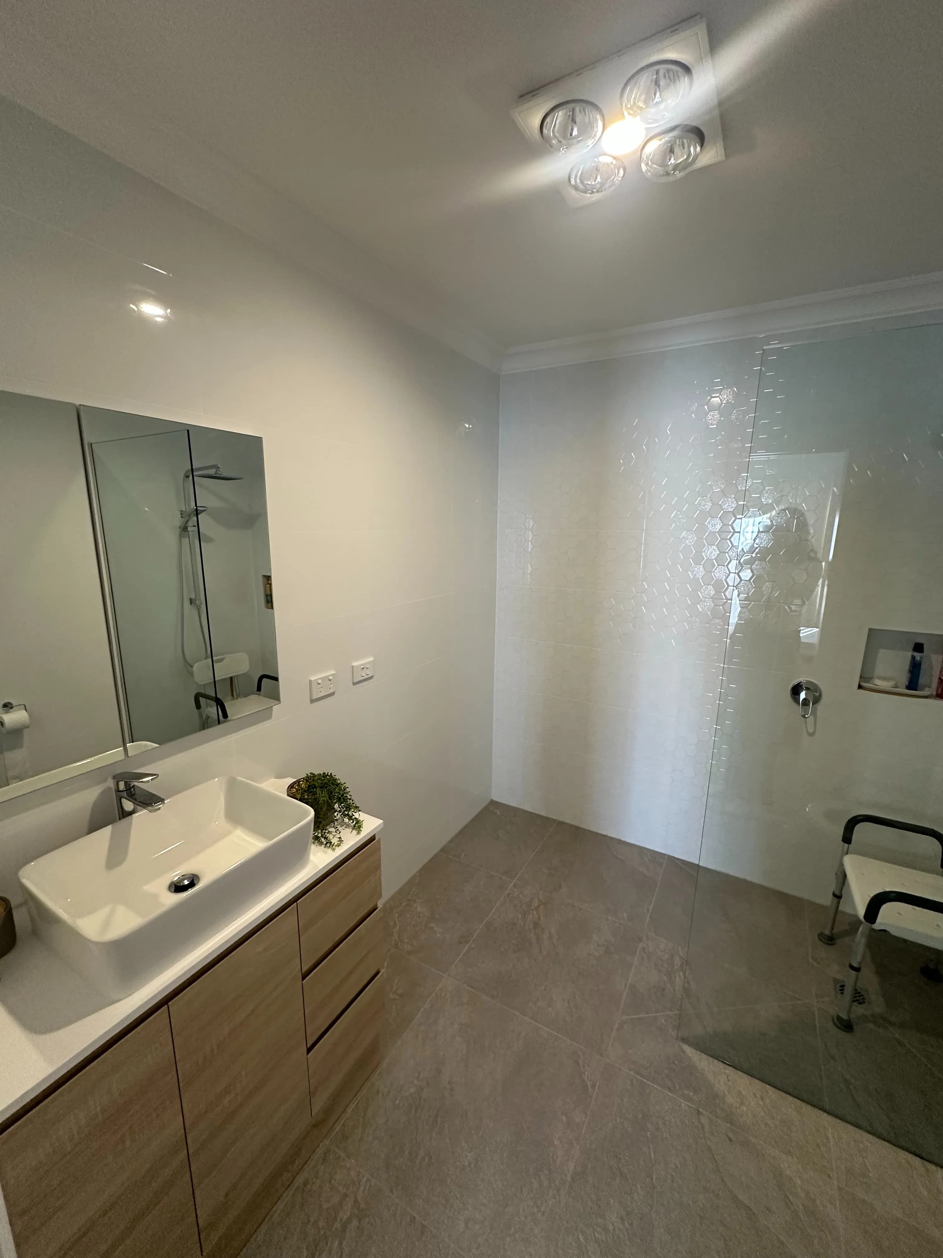 A completed accessible bathroom seen through its doorway, with grab rails and a level-access shower