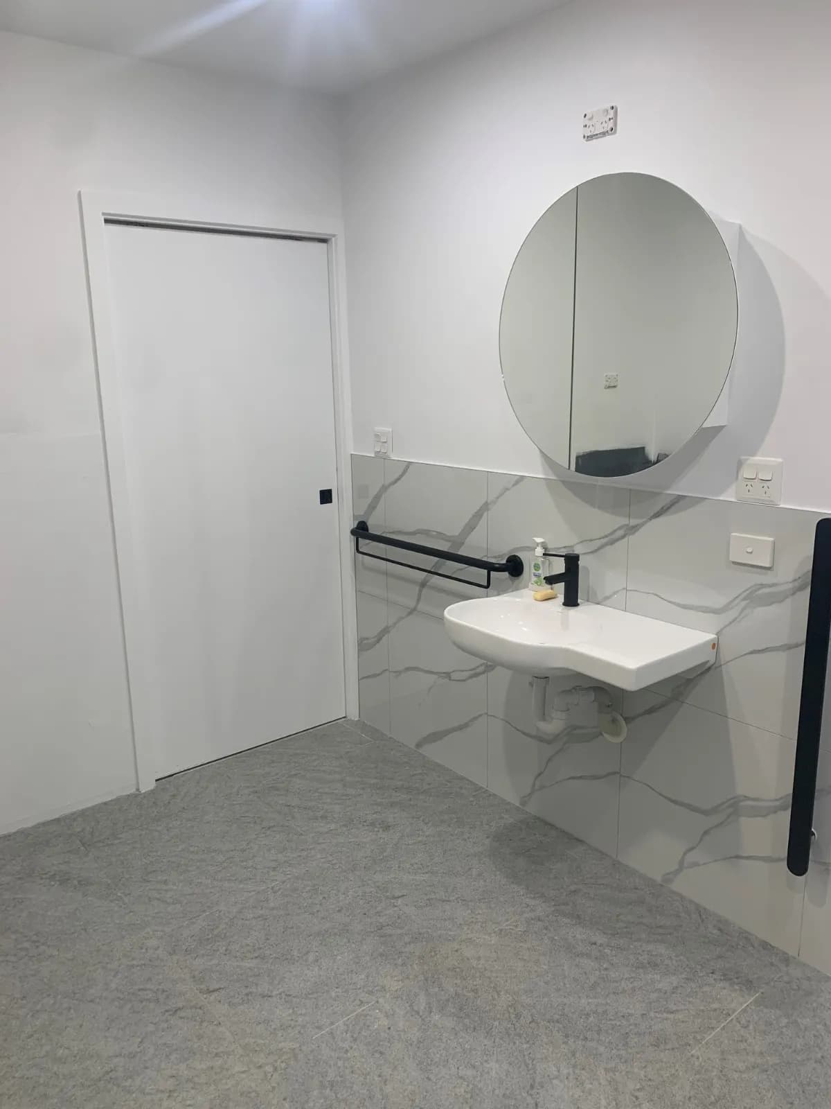 An accessible bathroom with a wall-hung basin at an approachable height and a mirror above it