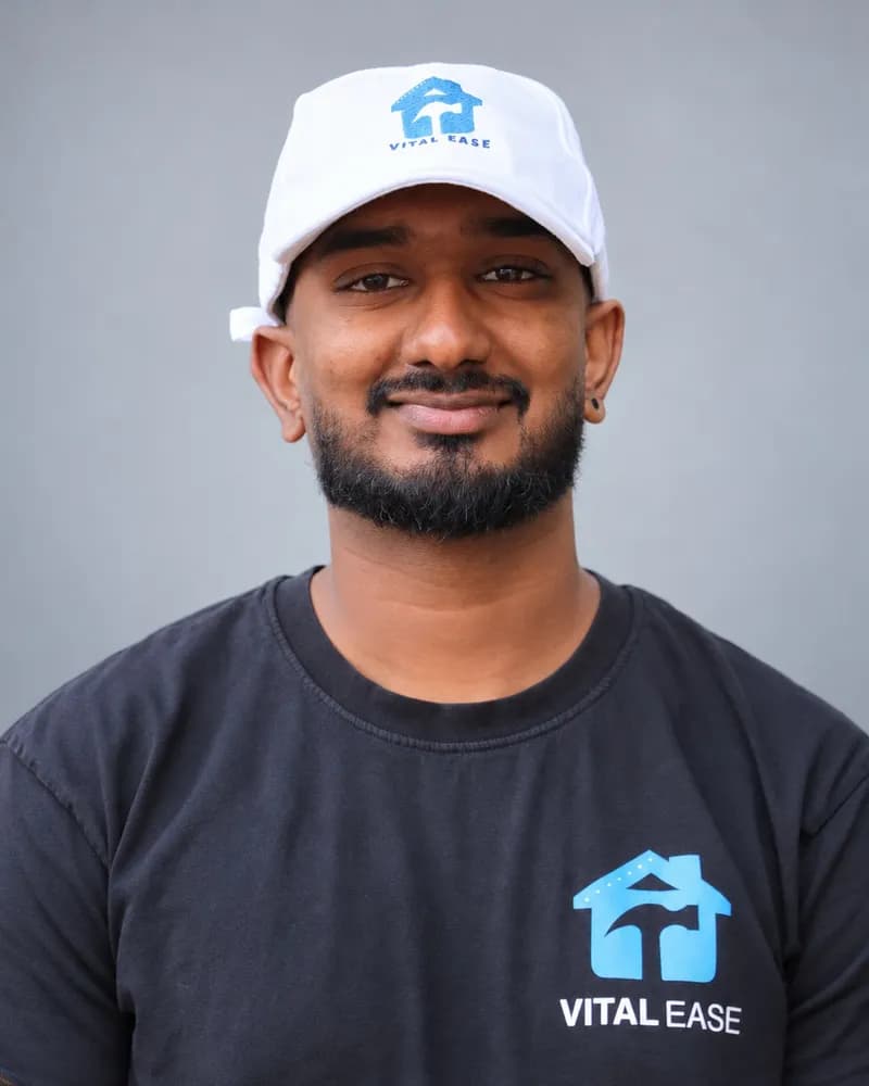 A smiling Vital Ease team member with a beard, in a white branded cap and dark T-shirt