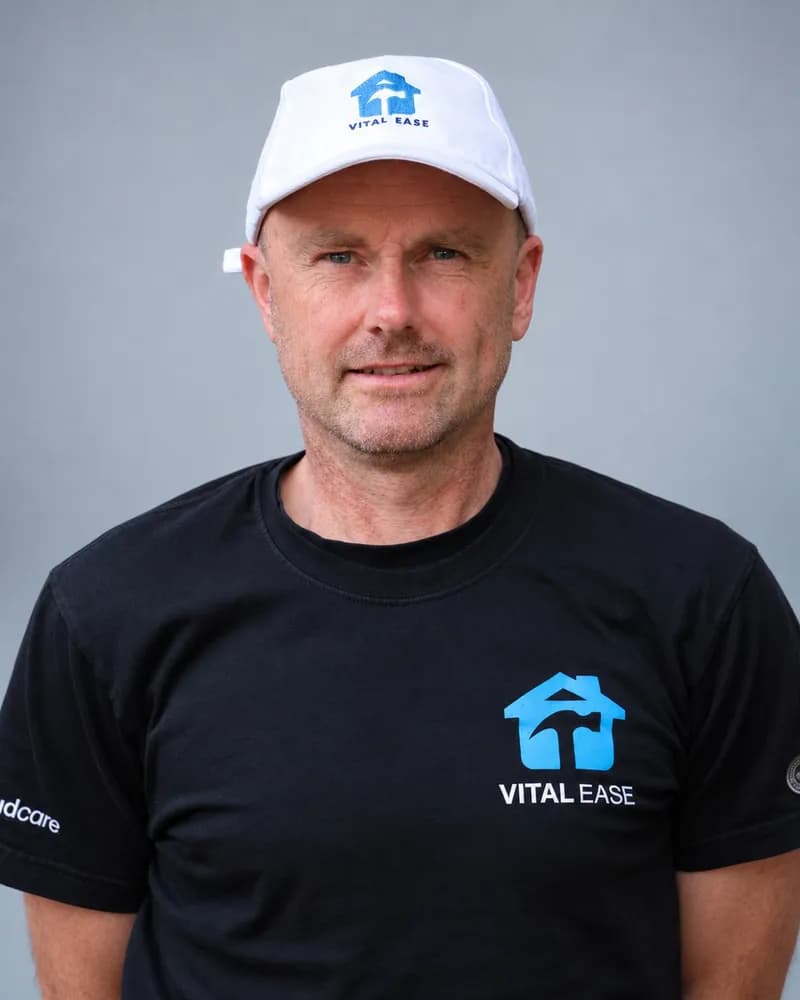 A Vital Ease team member in a white branded cap and black T-shirt