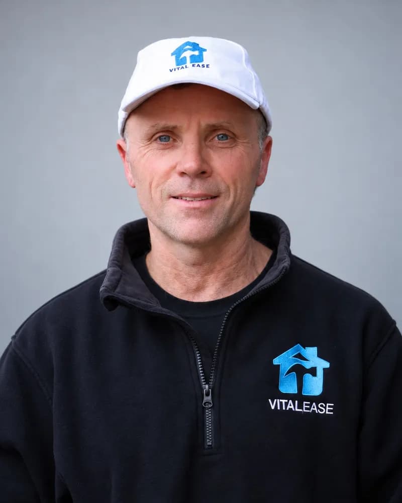 A Vital Ease team member in a white branded cap and black zip-up jacket
